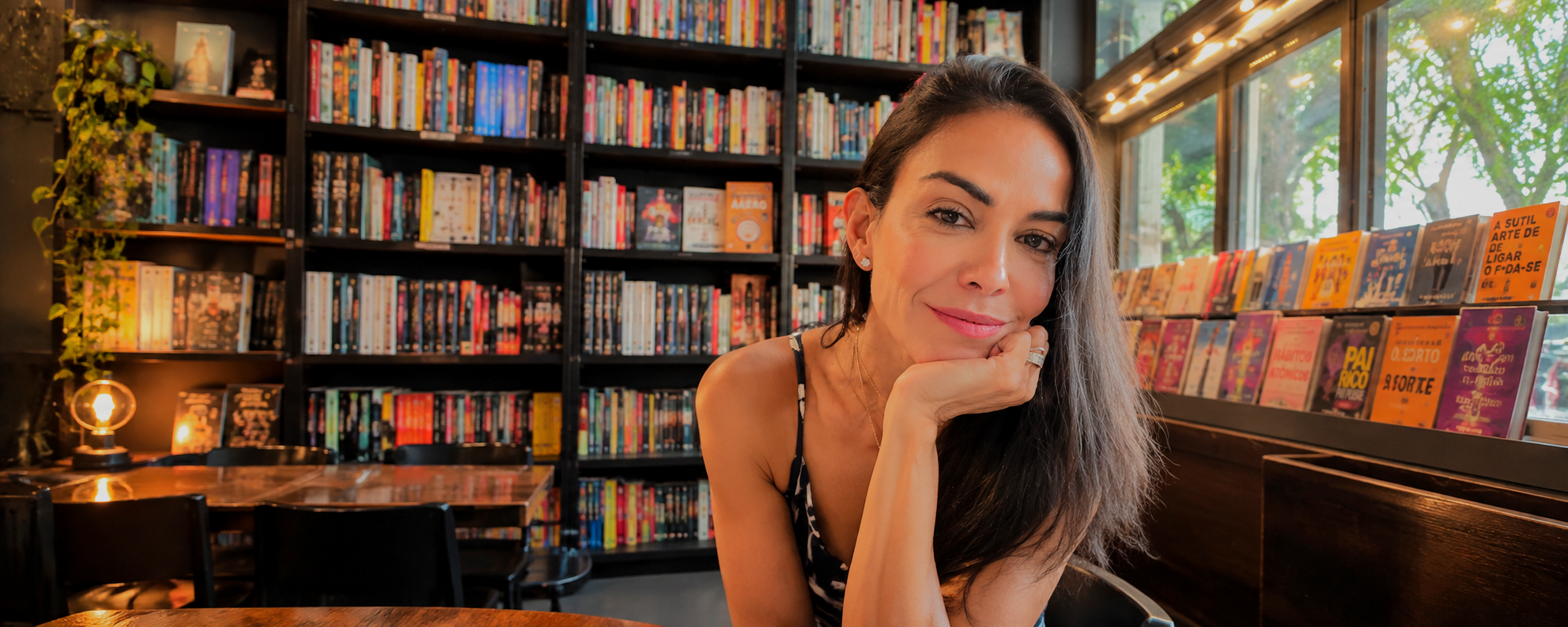 Lhyo em livraria, com estantes de livros ao fundo